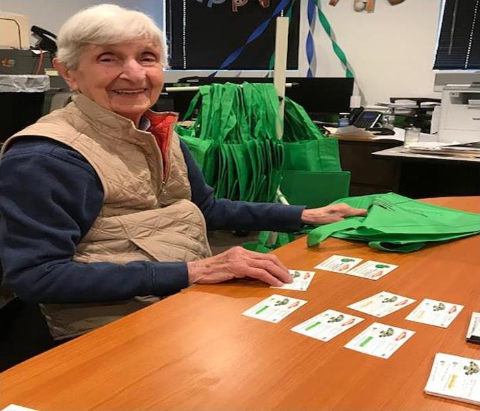 A woman sitting at a desk with SERVPRO cards and green bags