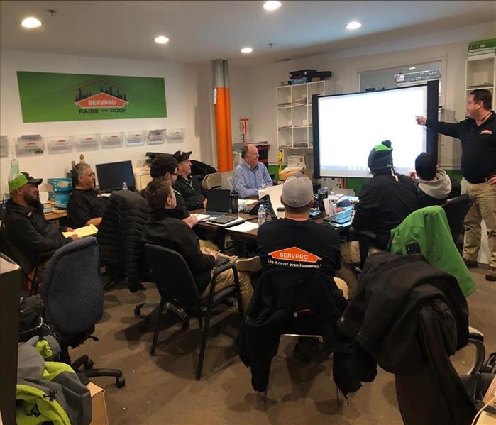 A group of people sitting in a room looking at a projector for SERVPRO 