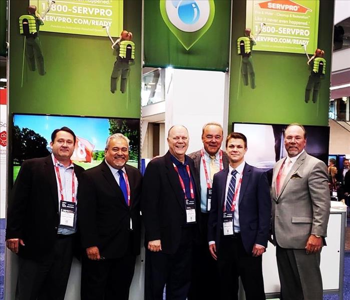 A group of men standing in front of SERVPRO banners 