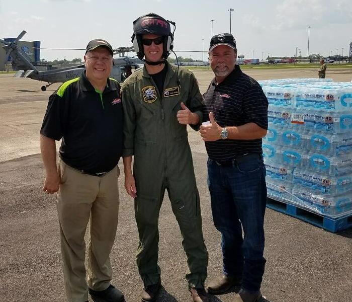 Two SERVPRO employees standing with a man with a helmet on