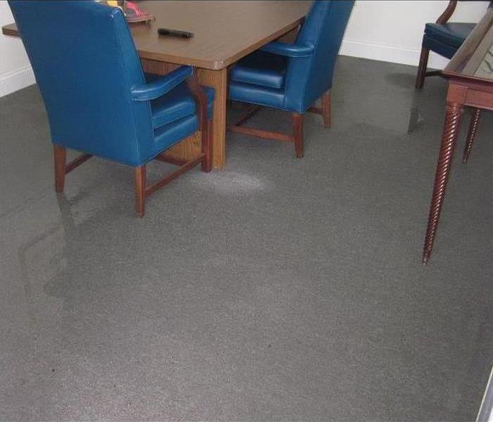 Standing water on carpet flooring with blue chairs and desk