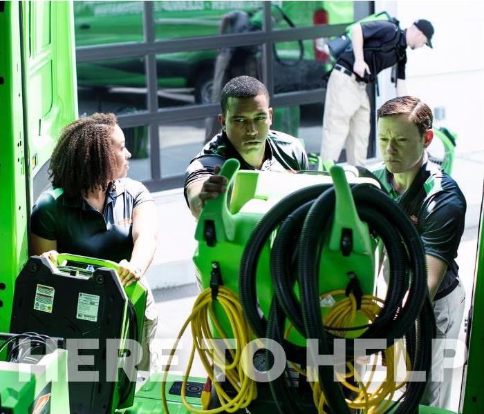 employees unloading water damage equipment from a van